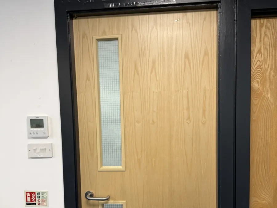 A fire door with a vision panel and a fire extinguisher beside it